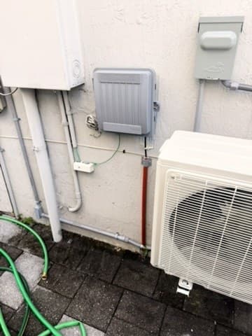 Mini-split condenser installed by AirWise outside a Miami-Dade home, next to its disconnect